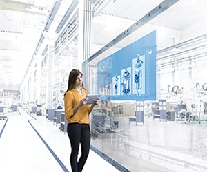 Young woman in factory, watching conveyor belt, holding digital tablet