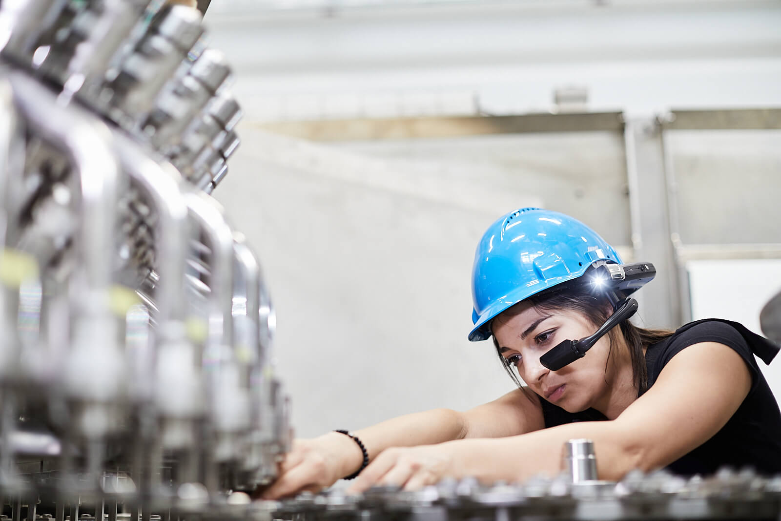 Woman-inspecting-bottling-machine-wearing-smart-glasses-and-safety-helmet_Copyright-TeamViewer